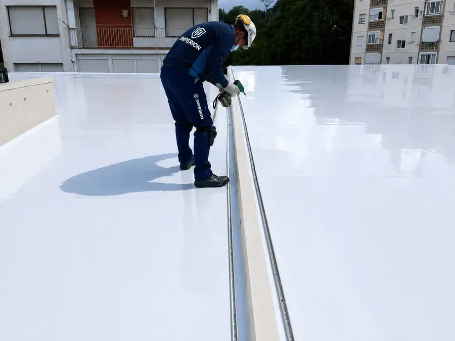 Operario de Imperion Tecpro rematando una cubierta blanca terminada en un edificio residencial